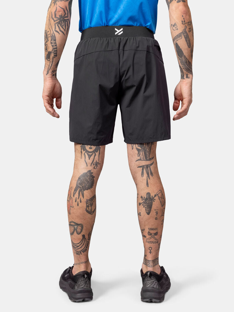 Halti Uurto Shortsit Miesten ja siniseen paitaan pukeutunut henkilö selästä kuvattuna, jolla on tatuoidut kädet ja jalat.