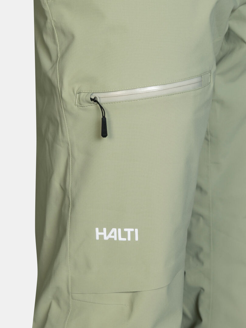 Vaaleanvihreät Halti Carvey II DX Lasketteluhousut Miesten -lasketteluhousut, joissa on vetoketjullinen reisitasku ja valkoinen logo lahkeessa.