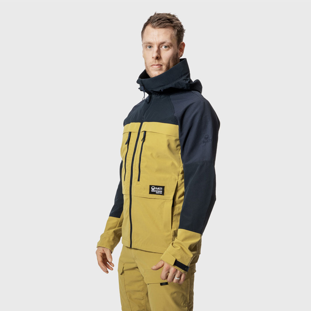 Mies Halti Hiker Miesten Lite Ulkoilutakki kierrätetystä nylonista seisoo sivuttain tasaista taustaa vasten.