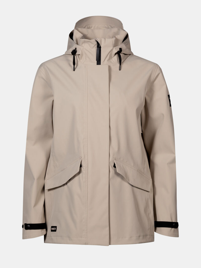 Halti Tokoi DX Takki Naisten - beige vedenpitävä hupullinen takki mustilla vetoketjuilla ja läppätaskuilla, valkoisella taustalla.