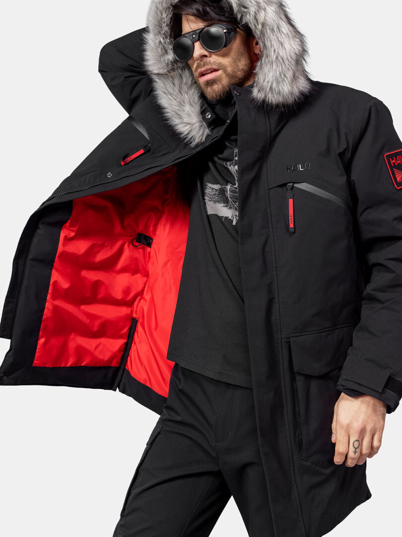 Aurinkolasipäinen mies mallina Halti 1976 Down Parka Unisex, jossa on tekoturkishuppu ja punainen vuori.