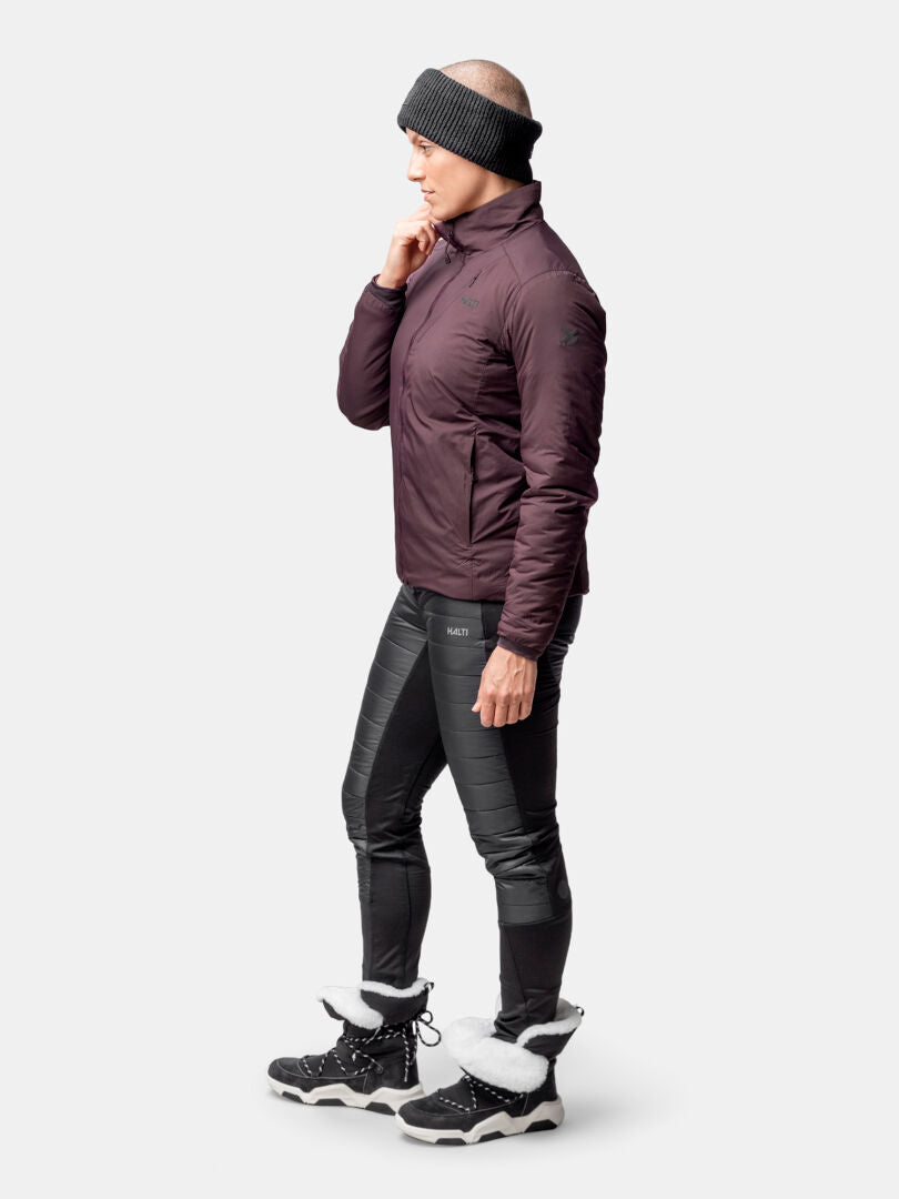 Henkilö profiilissa yllään Halti Haave Primaloft Takki Naisten, mustat leggingsit, talvisaappaat ja neulottu päähine.