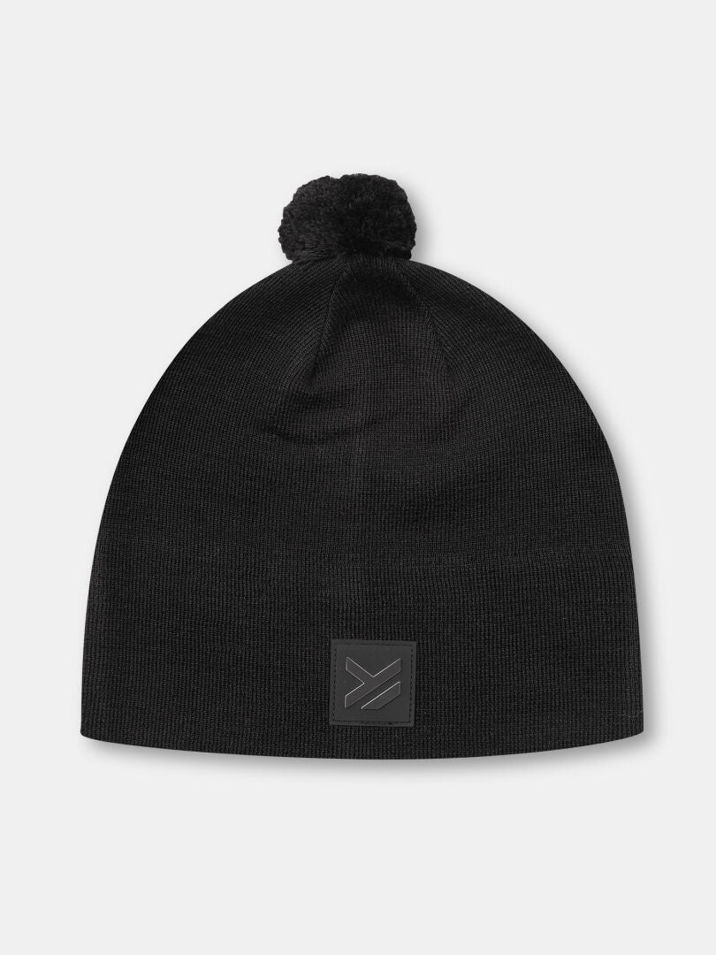 Halti Pilke Pipo on musta merinovillainen pipo, jossa on pom-pom ja minimalistinen logo – täydellinen valinta tyylikkääseen talviseen lämpöön.