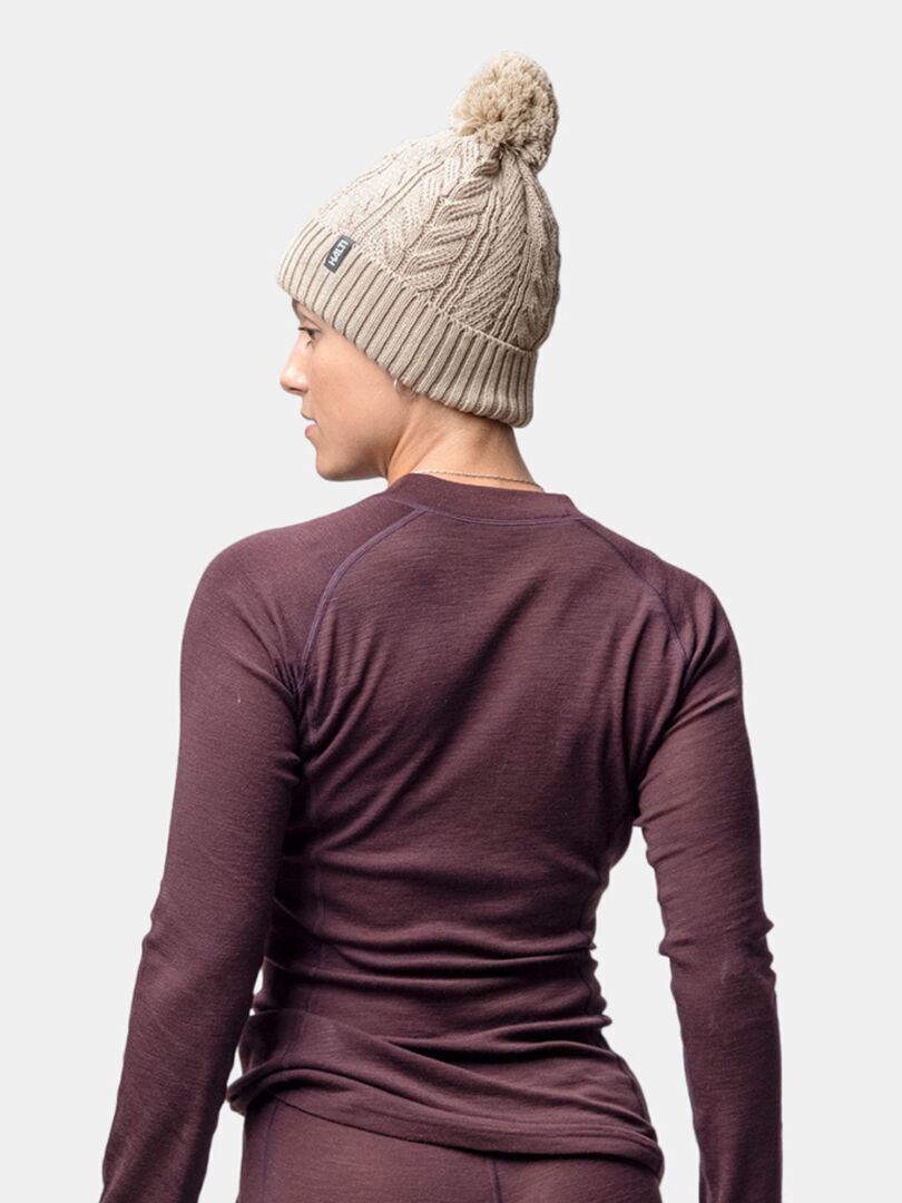 Henkilö, jolla on yllään beige Halti Hile Pipo ja pitkähihainen violetti toppi, katse poispäin kamerasta.