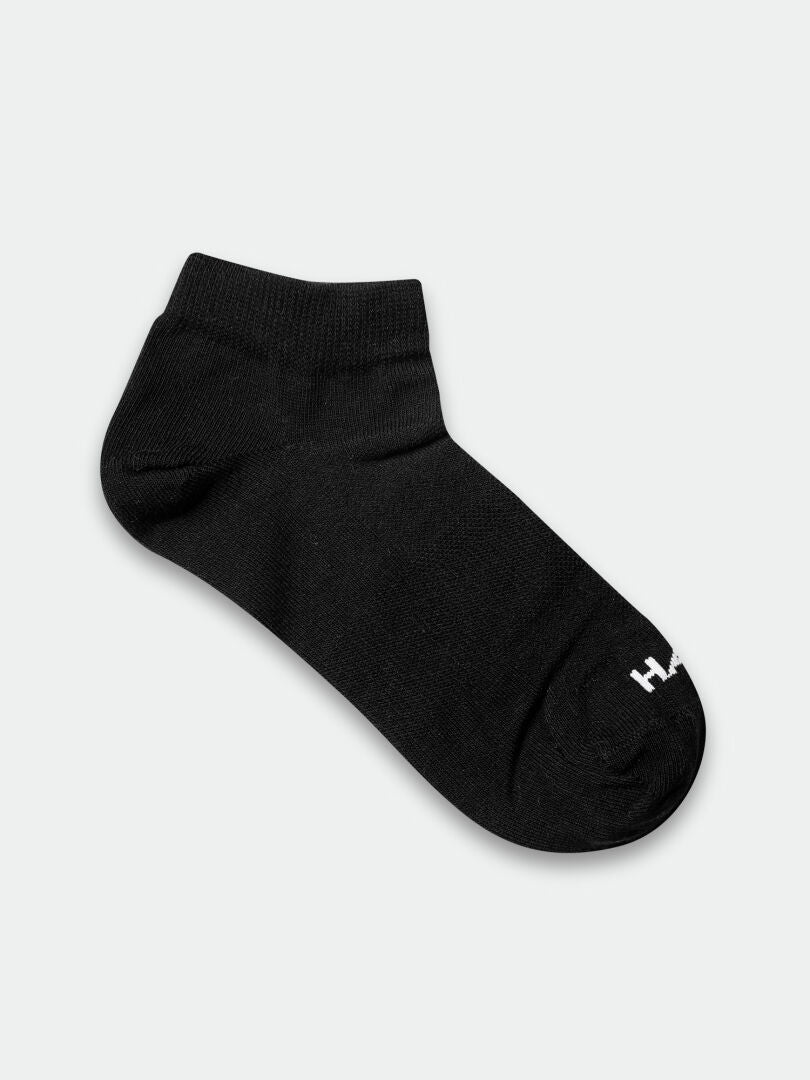 Yksi musta Halti Outdoor Sport Low Sukat -kenkä, jossa pieni valkoinen logo varvassa, vaalealla pohjalla.