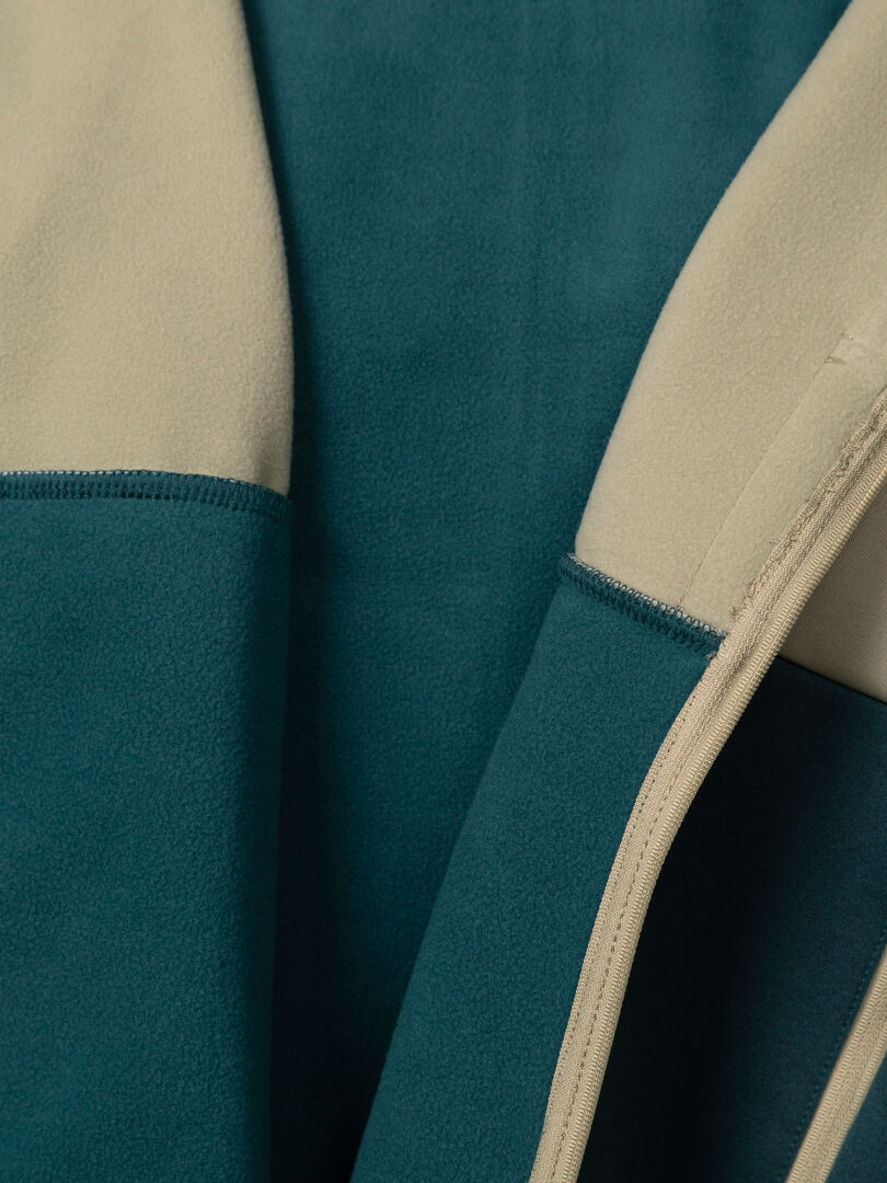 Lähikuva sinivihreästä ja beigeestä Halti Seiland Välitakki Naisten -fleece-takista, jossa on edessä vetoketju.