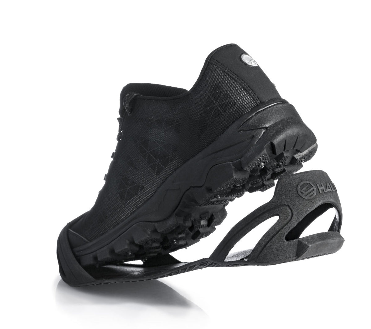 Halti Shoecover -kenkäsuoja nastakengille on musta urheilukenkä, jossa on TR-kumi-pitopohja (kuvassa valkoinen).